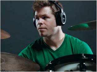 This is a picture of a man using the AWD210 headphones wile playing drums