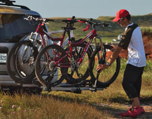 A mountain biker using the Thule 918XT T2 2 Inch Receiver 2-Bike Add-on Hitch Rack at a trailhead