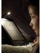 Kindle e-reader: reads like real paper, as shown by young girl reading a Kindle in bed, with the lights off and using a Kindle lighted cover