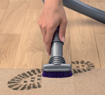 Using the stubborn dirt brush to remove a dirty footprint from a floor