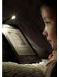 Liseuse Kindle : se lit comme un livre papier, comme le montre la petite fille sur son lit, qui lit sur Kindle avec les lumières éteintes à l'aide d'une lampe de lecture.