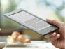 Liseuse Kindle : appareil tenu en main, lecture dans un caf�